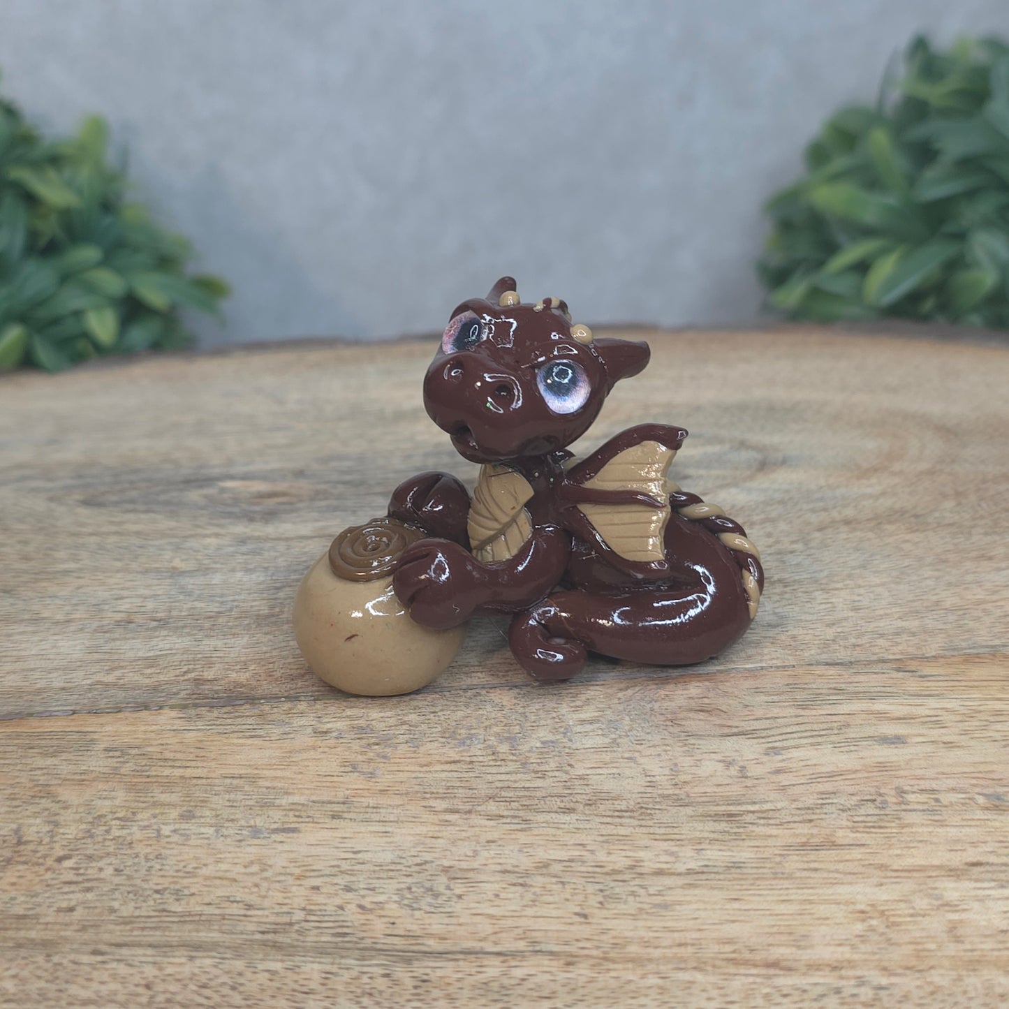 A baby polymer clay dragon with a chocolate truffle against a blurred background