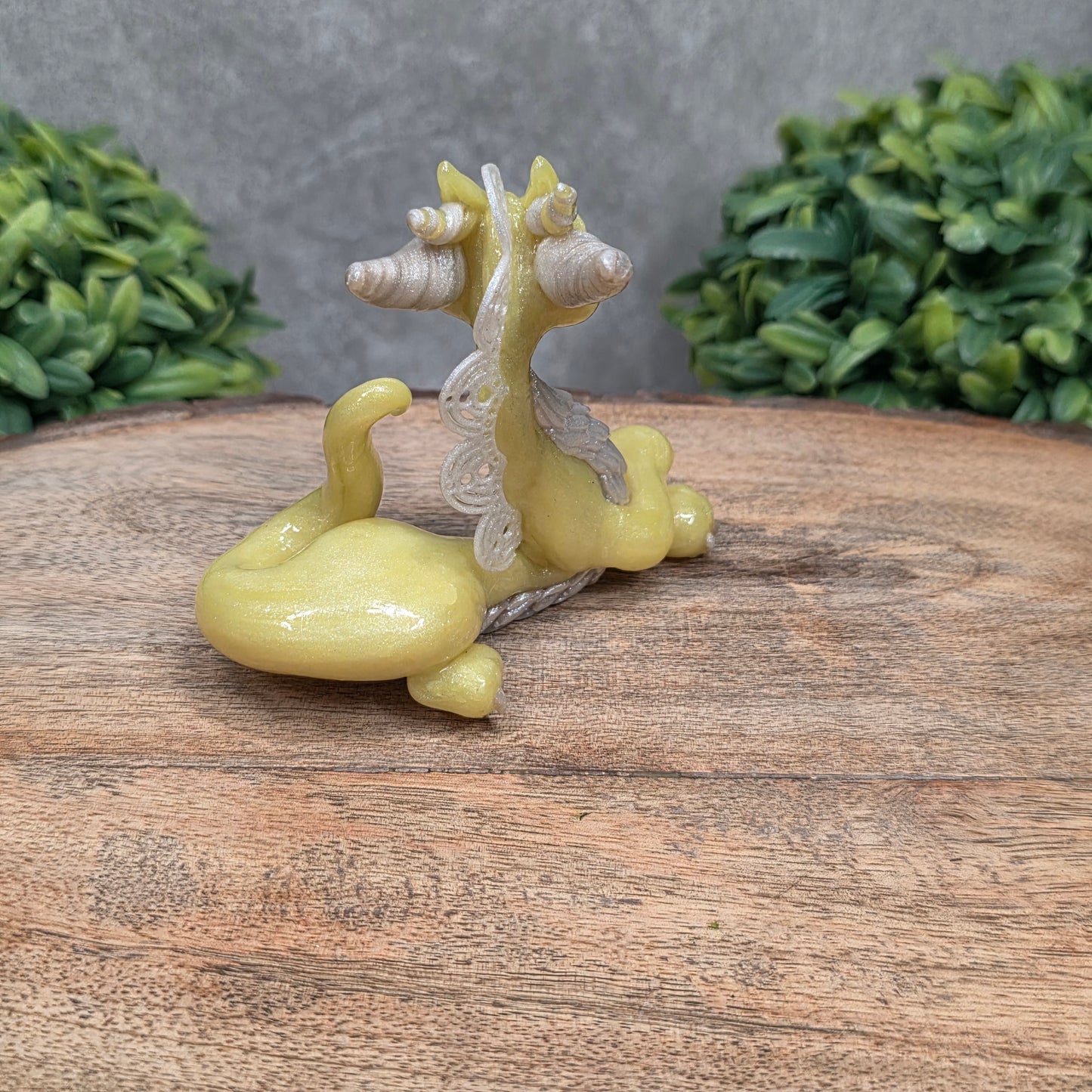 A dragon sculpture on wood surface with greenery