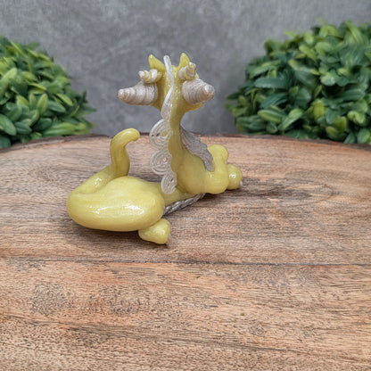 A dragon sculpture on wood surface with greenery