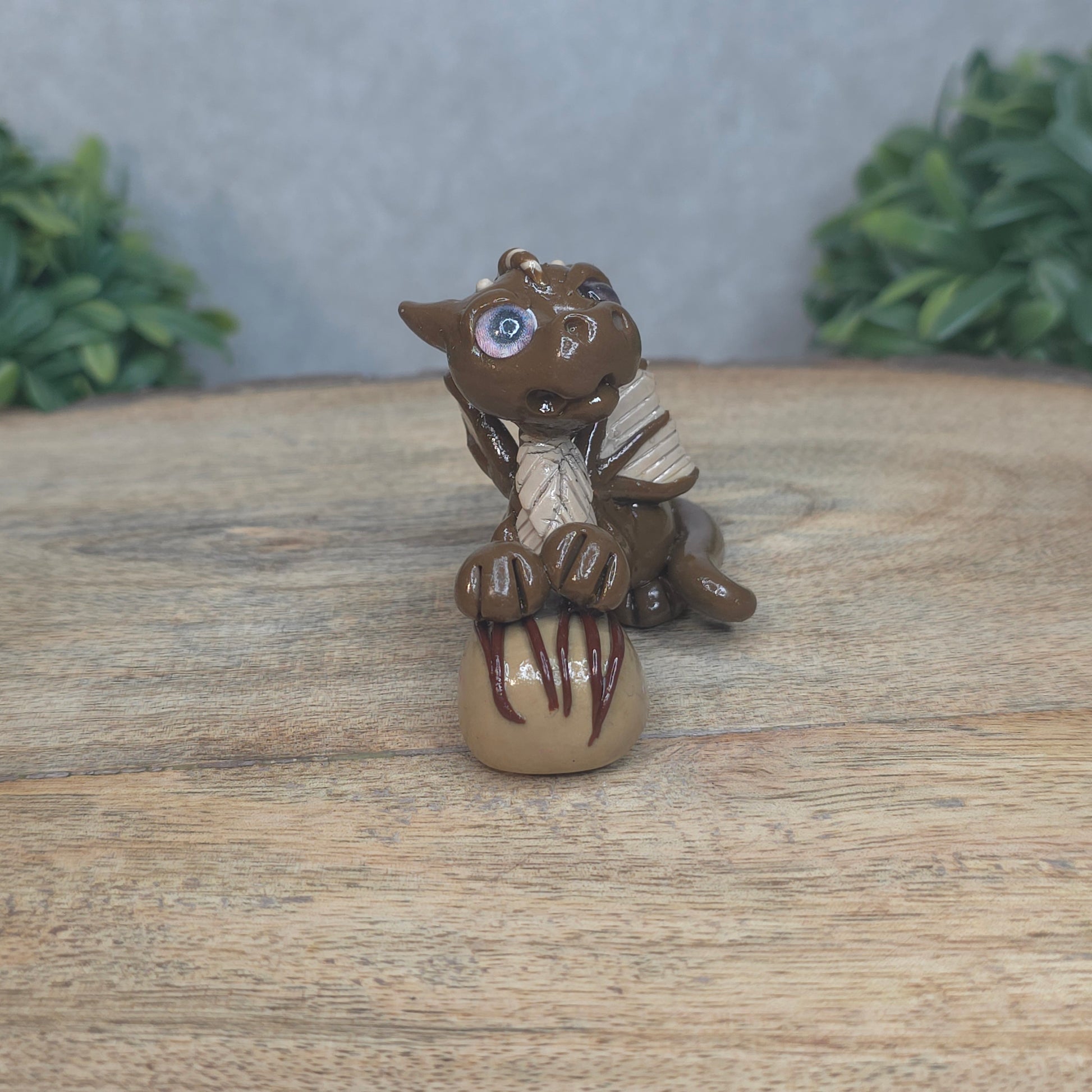 A baby polymer clay dragon with a chocolate truffle against a blurred background