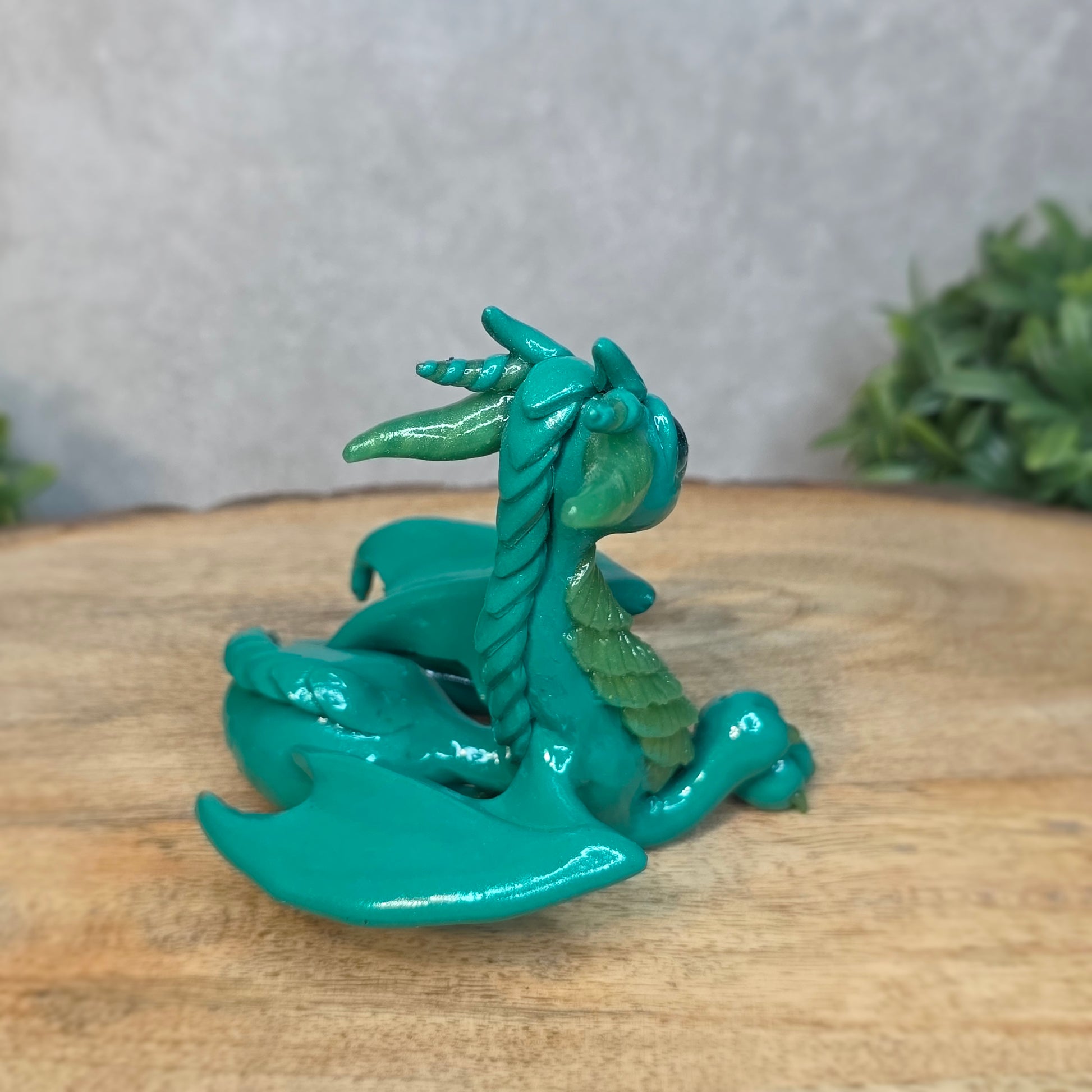 A green clay dragon against a blurred wood surface