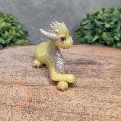A dragon sculpture on wood surface with greenery