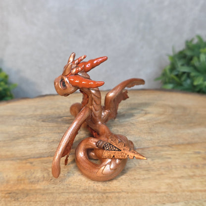 Copper dragon figurine on a wood surface with a blurred background