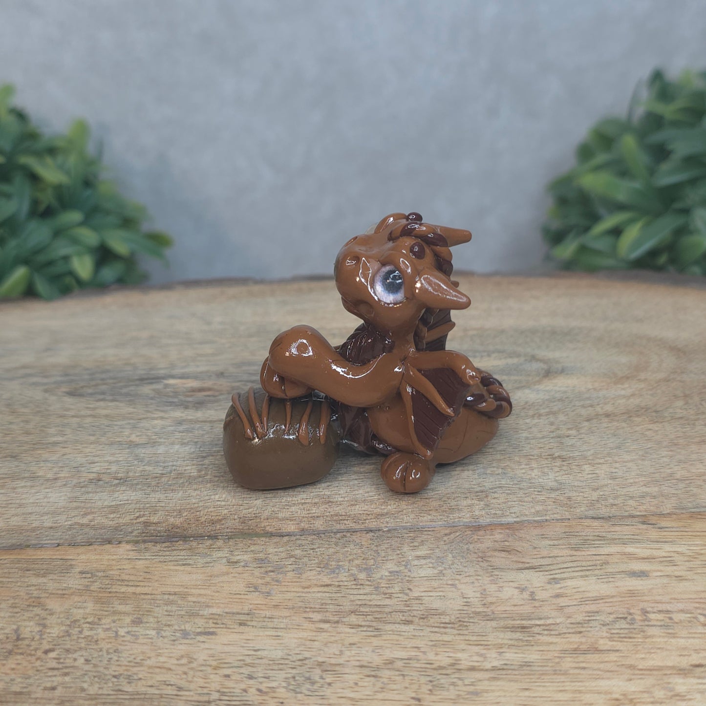 A baby polymer clay dragon with a chocolate truffle against a blurred background