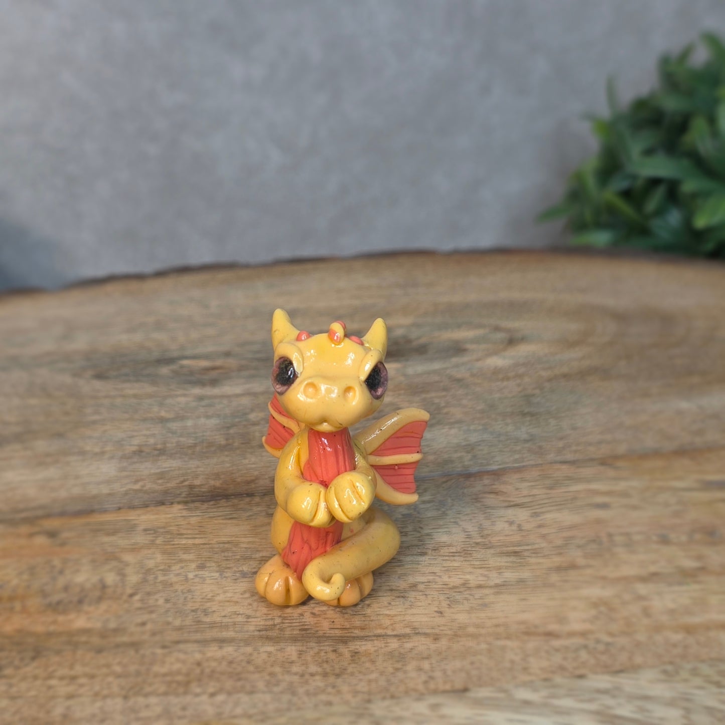 A small peach dragon against a blurred wood background