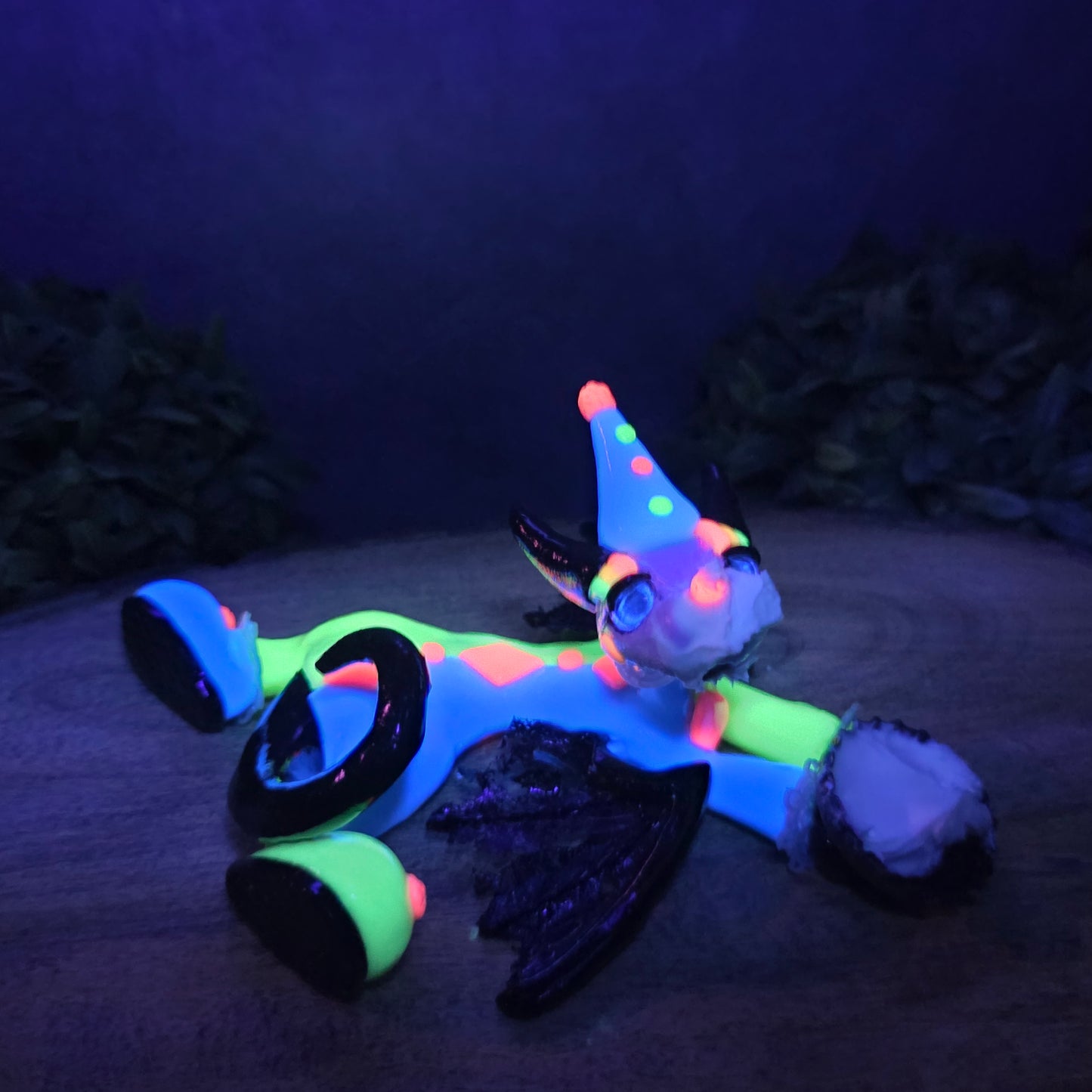 A blacklight reactive clown dragon with a cream pie on face