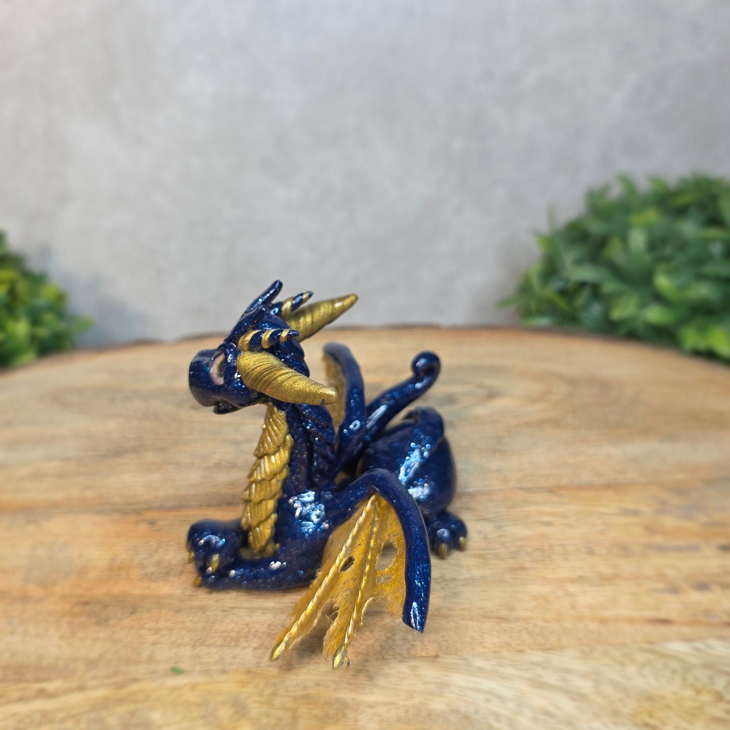 A blue and gold clay dragon against a blurred wood surface