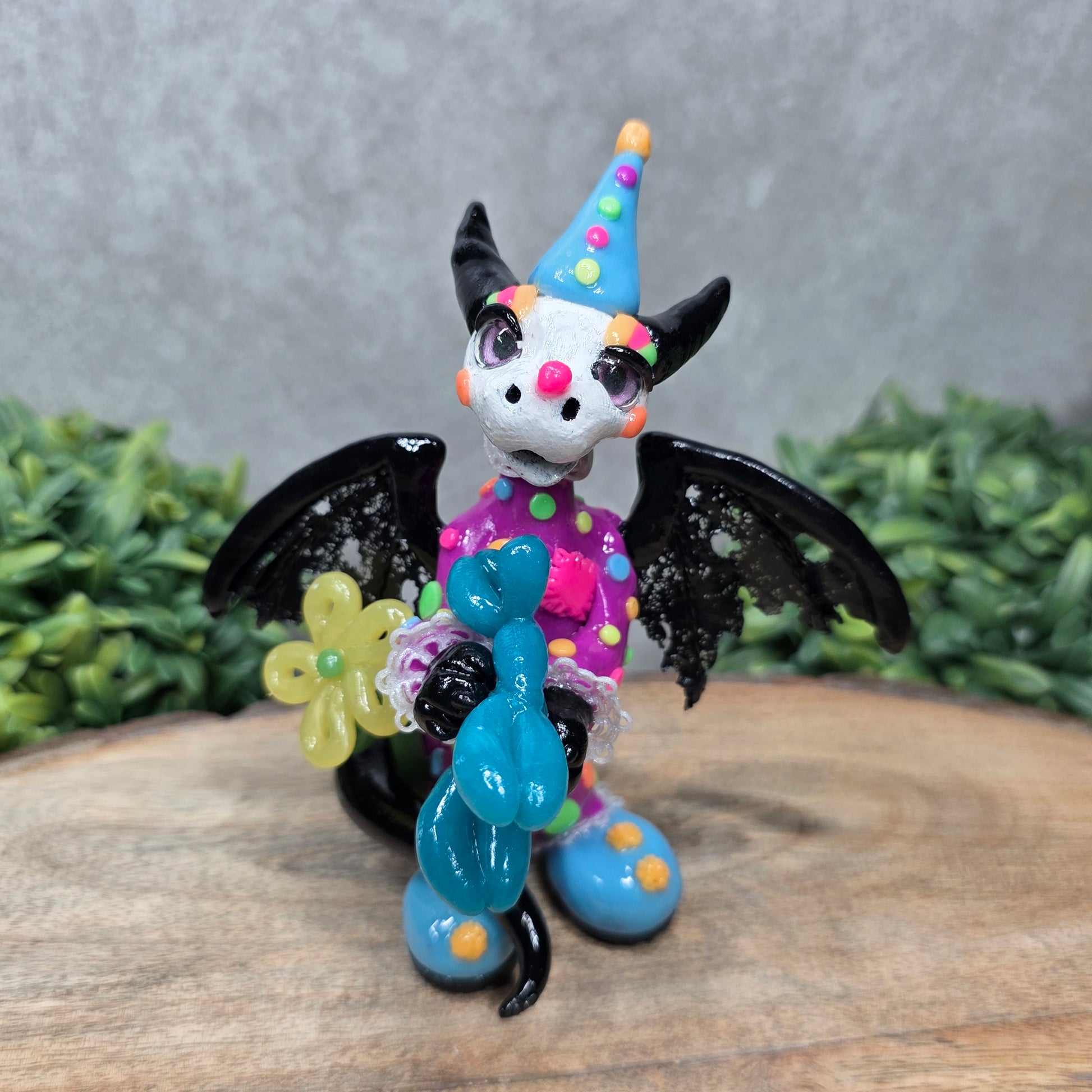 A clown dragon with balloon animals on wood surface with greenery