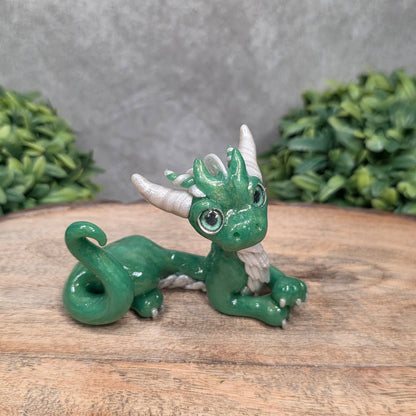 A dragon sculpture on wood surface with greenery