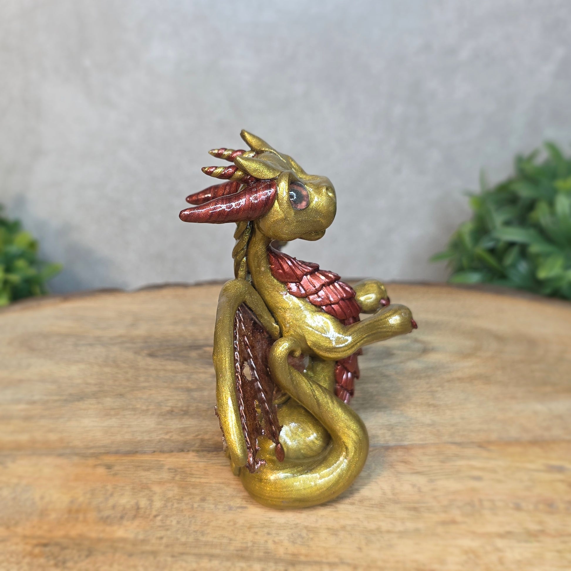 A gold and bronze clay dragon against a blurred wood surface