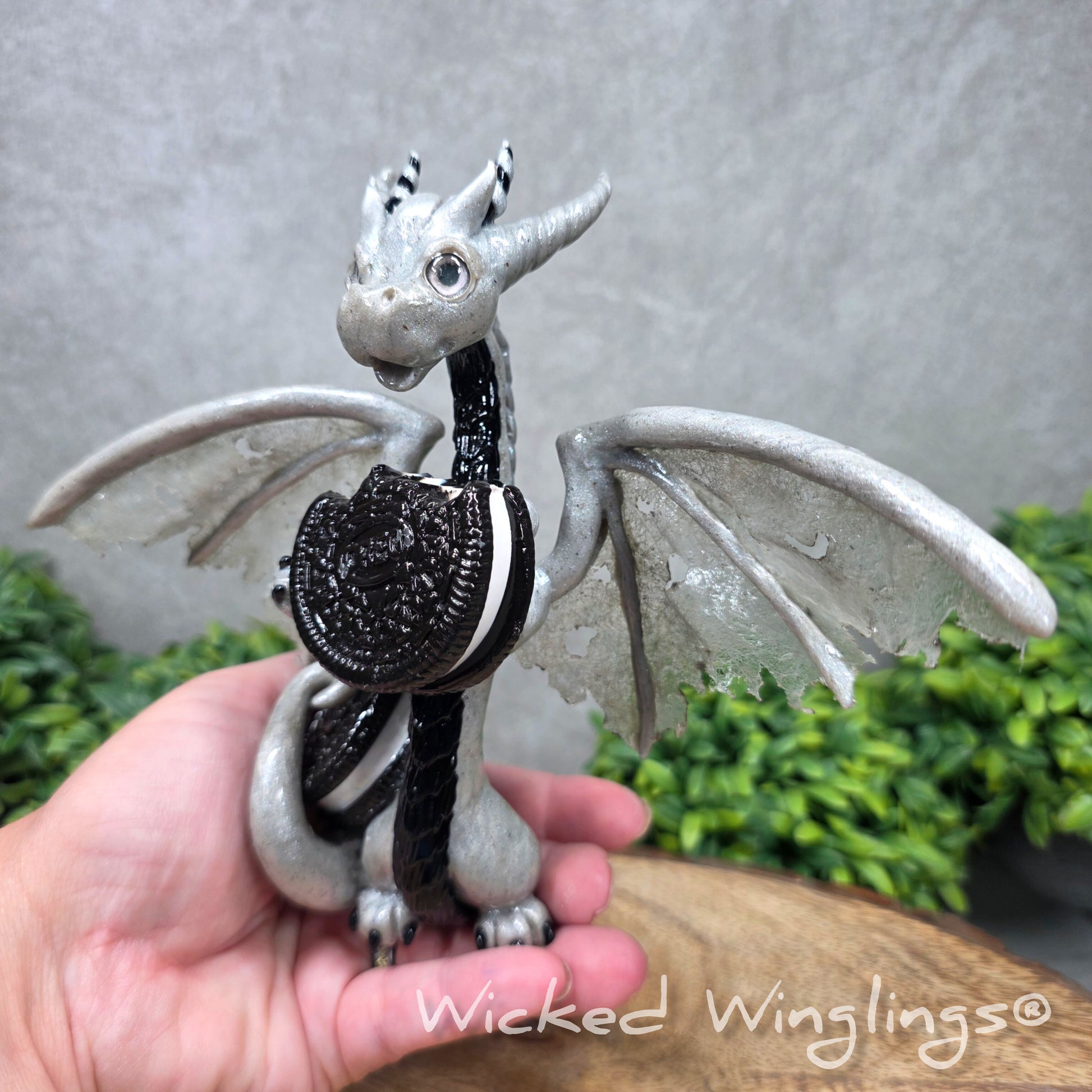  hand holding a  large clay dragon with cookies with a Wicked Winglings® watermark.