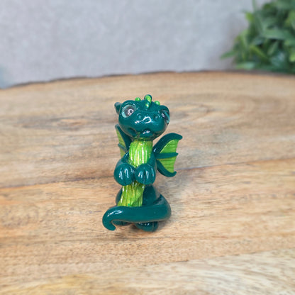 A small green dragon against a blurred wood background