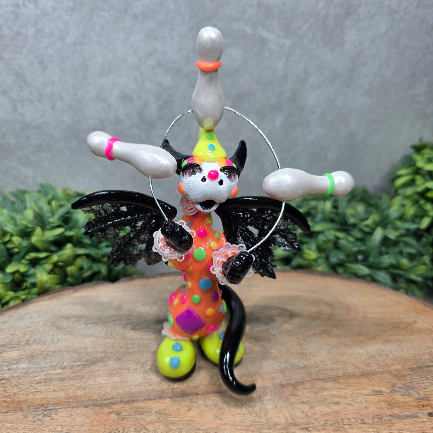 A clown dragon juggling on a wood surface with greenery