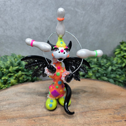 A clown dragon juggling on a wood surface with greenery