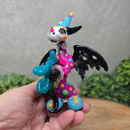 A clown dragon with balloon animals on wood surface with greenery