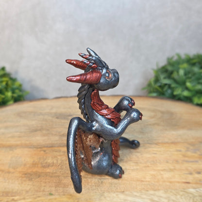 A graphite and bronze clay dragon against a blurred wood surface
