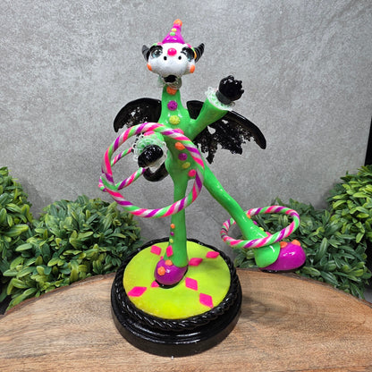 A clown dragon with hoola hoops on a wood surface with greenery