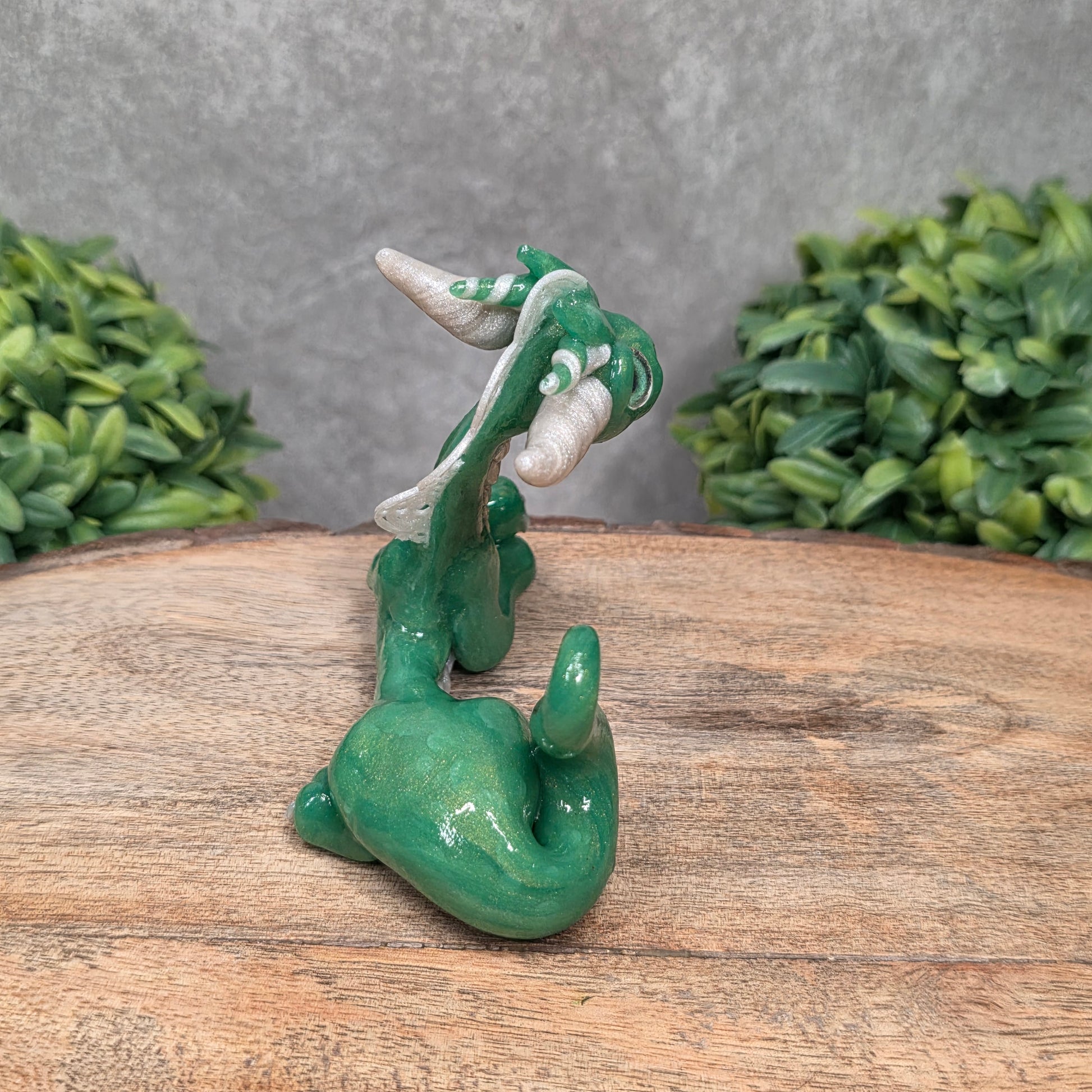 A dragon sculpture on wood surface with greenery