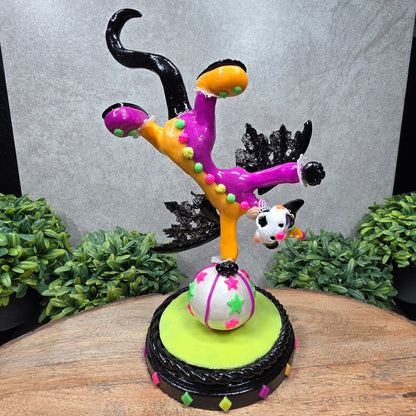 A clown dragon balancing on a ball on a wood surface with greenery