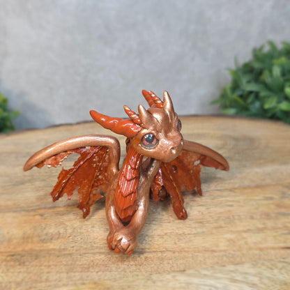Copper dragon figurine on a wood surface with a blurred background