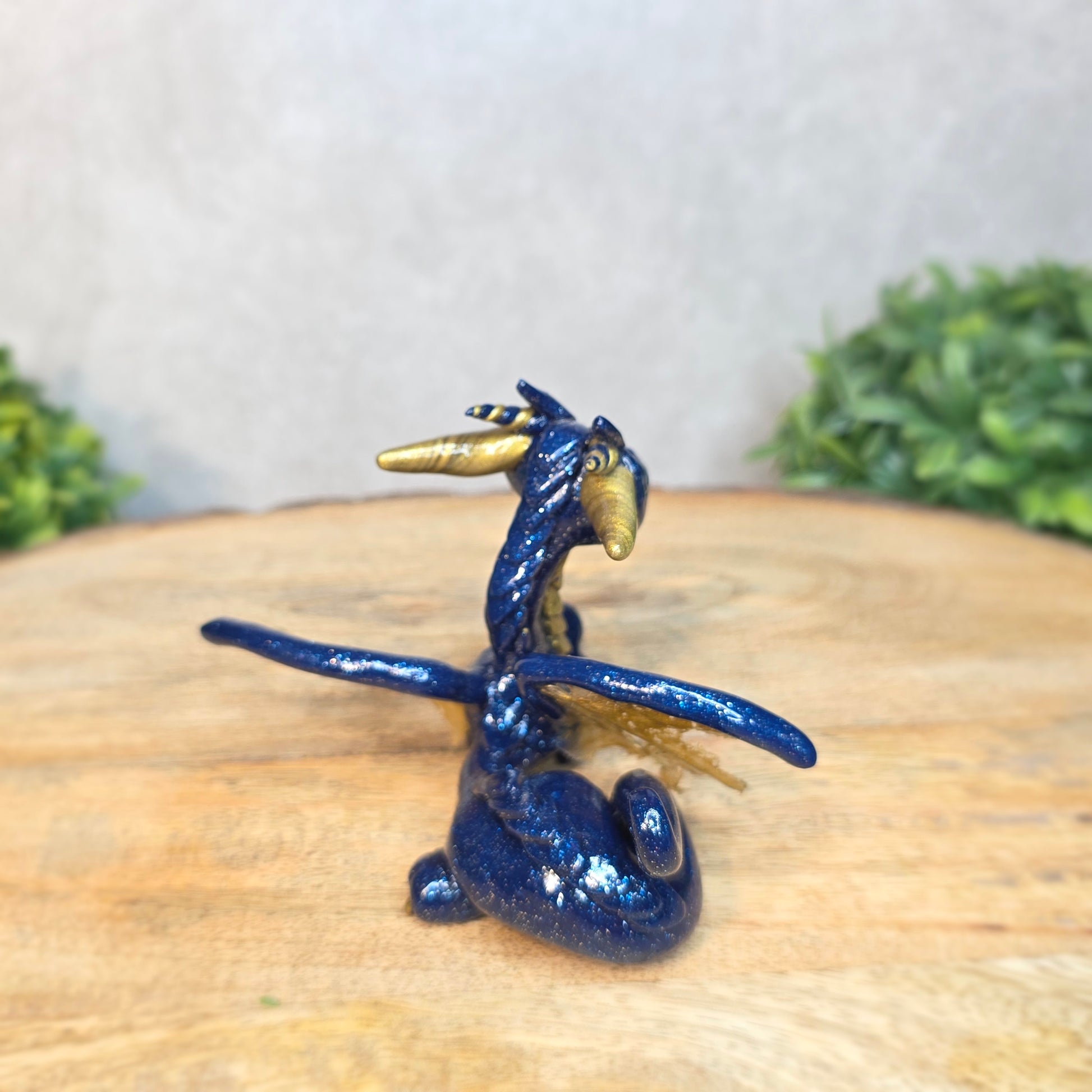A blue and gold clay dragon against a blurred wood surface