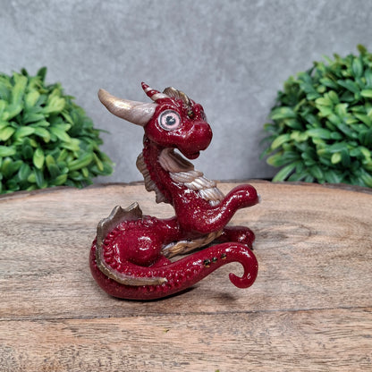 A clay dragon against a wood background with greenery