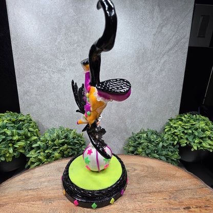 A clown dragon balancing on a ball on a wood surface with greenery