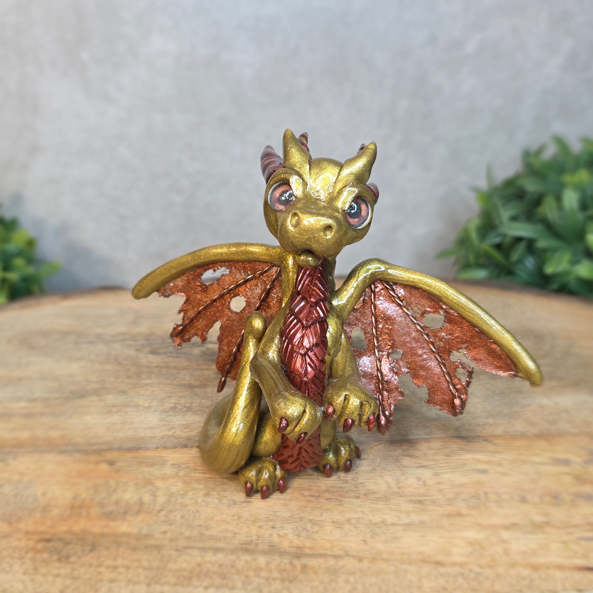 A gold and bronze clay dragon against a blurred wood surface