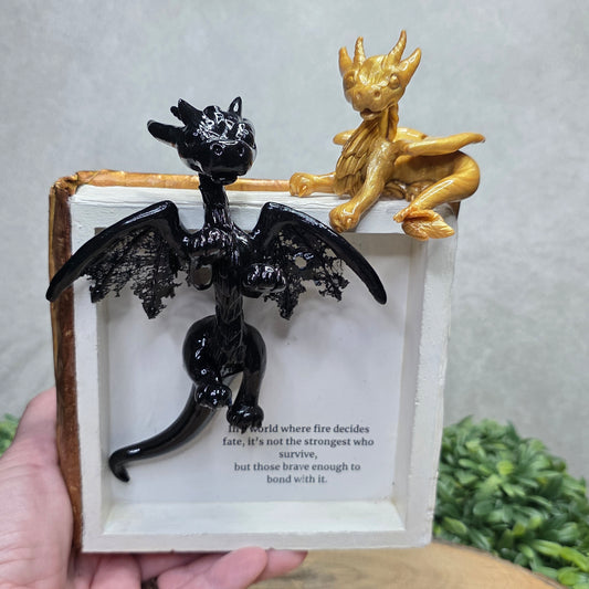Book nook with dragons on a wood surface with greenery