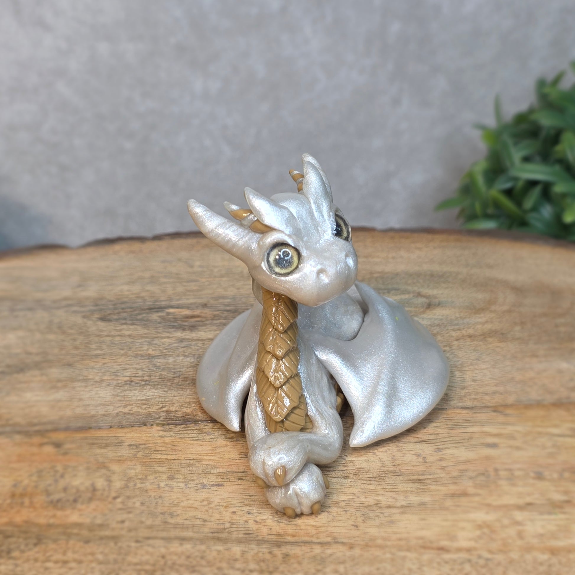 A pearl and tan clay dragon against a blurred wood surface