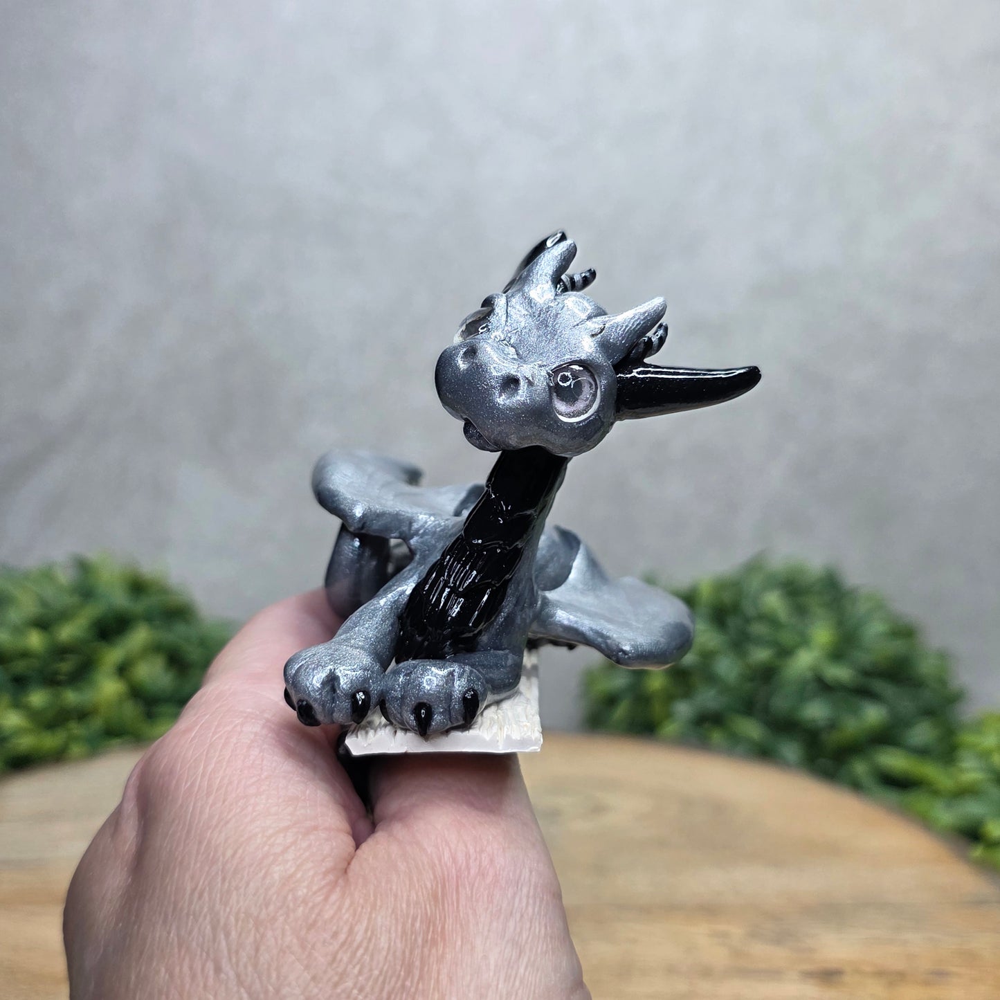 Hand holding a dragon book insert against a background with greenery