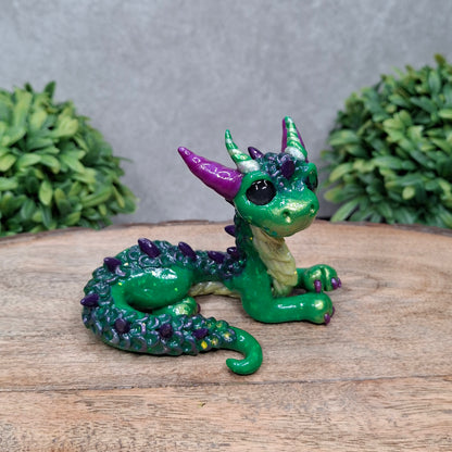 A clay dragon against a wood background with greenery
