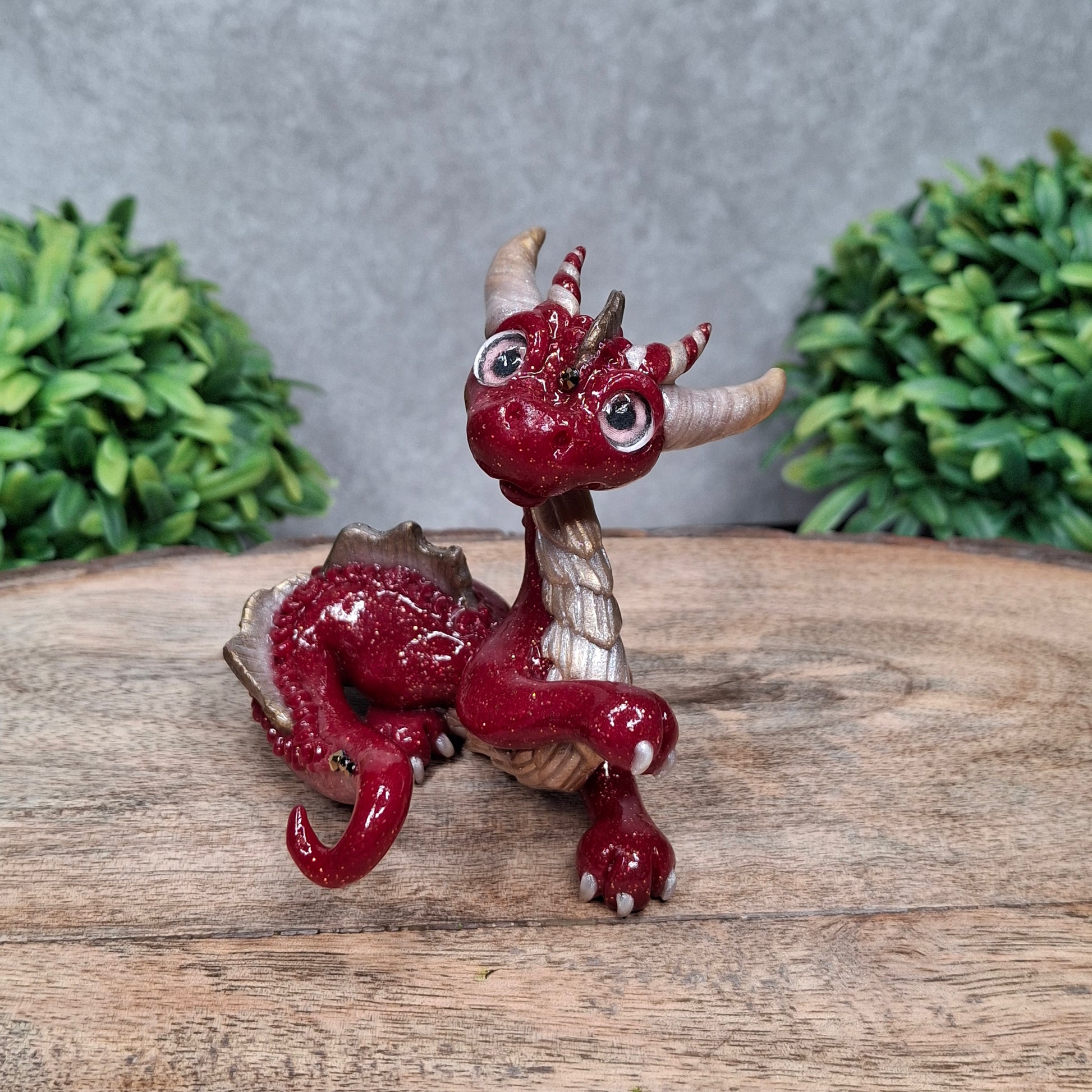 A clay dragon against a wood background with greenery