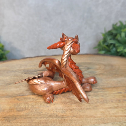 Copper dragon figurine on a wood surface with a blurred background