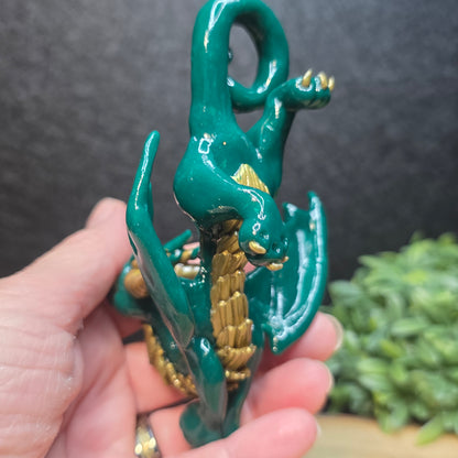 Hand holding a green and gold clay dragon