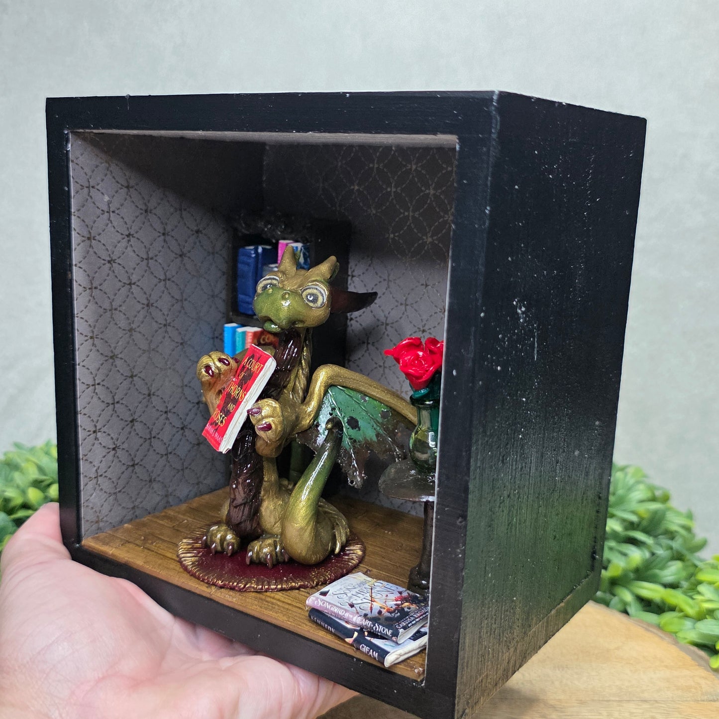 Book nook with dragon on a wood surface with greenery