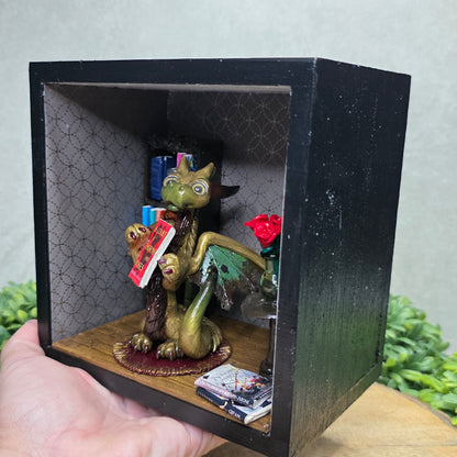 Book nook with dragon on a wood surface with greenery