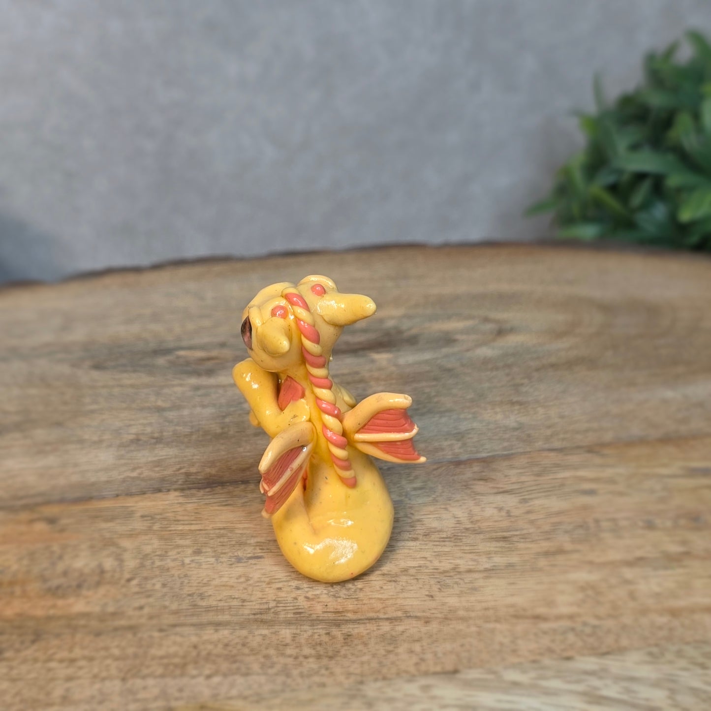A small peach dragon against a blurred wood background