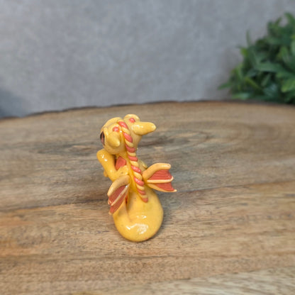 A small peach dragon against a blurred wood background
