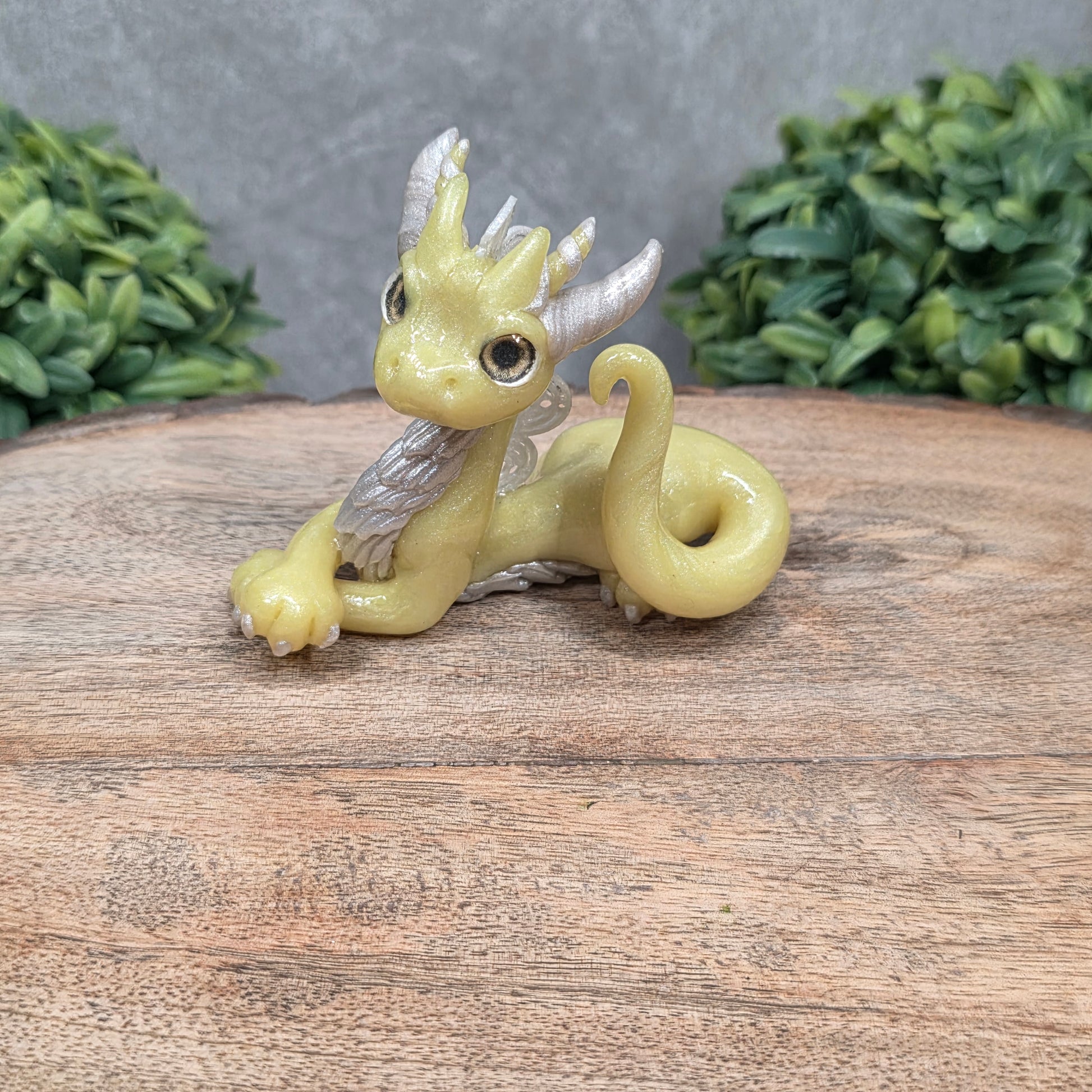 A dragon sculpture on wood surface with greenery