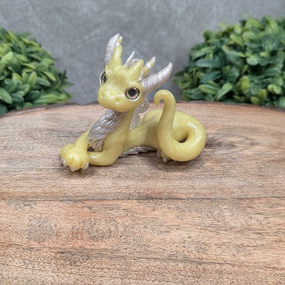 A dragon sculpture on wood surface with greenery