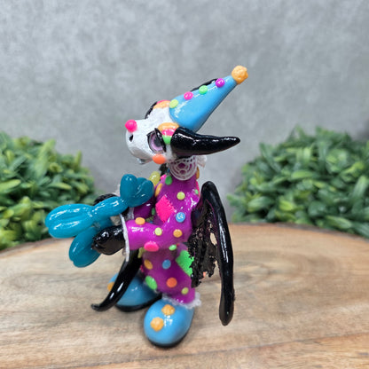 A clown dragon with balloon animals on wood surface with greenery