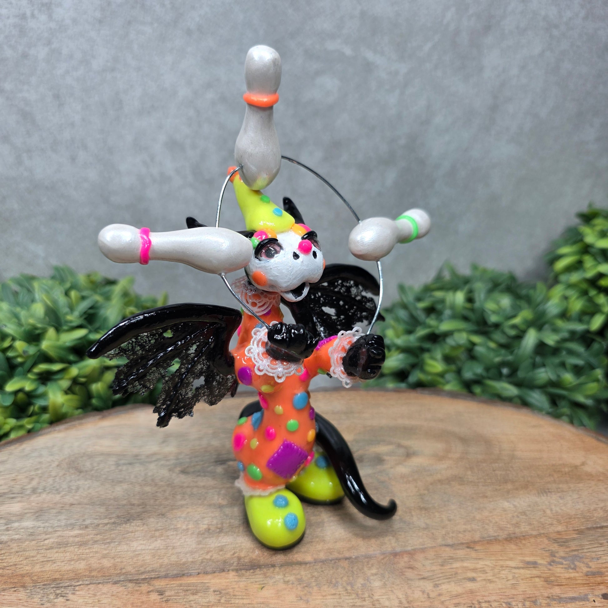 A clown dragon juggling on a wood surface with greenery