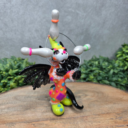A clown dragon juggling on a wood surface with greenery