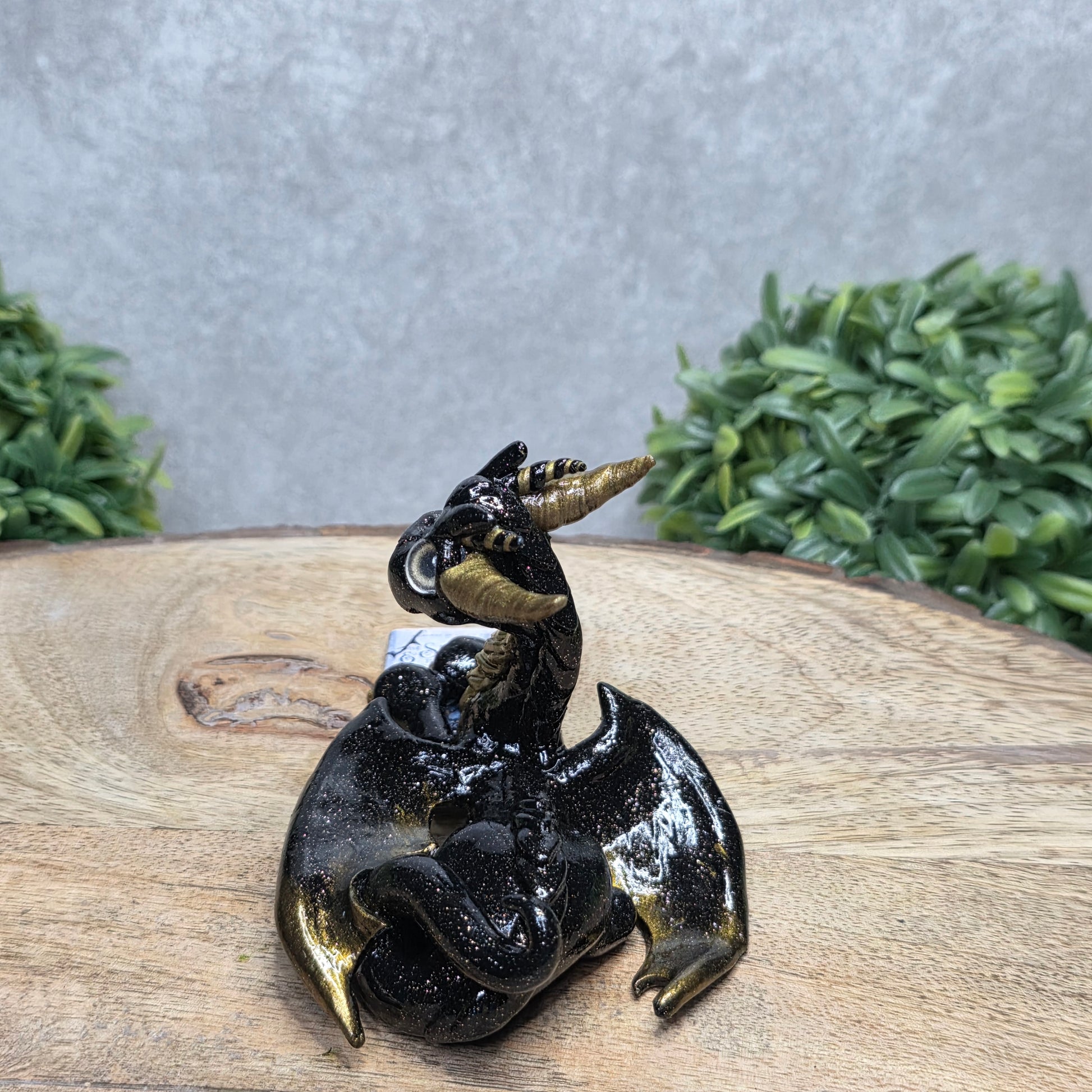 A dragon reading a book against a wood surface with greenery