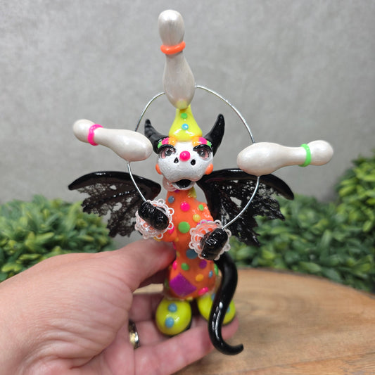 A clown dragon juggling on a wood surface with greenery
