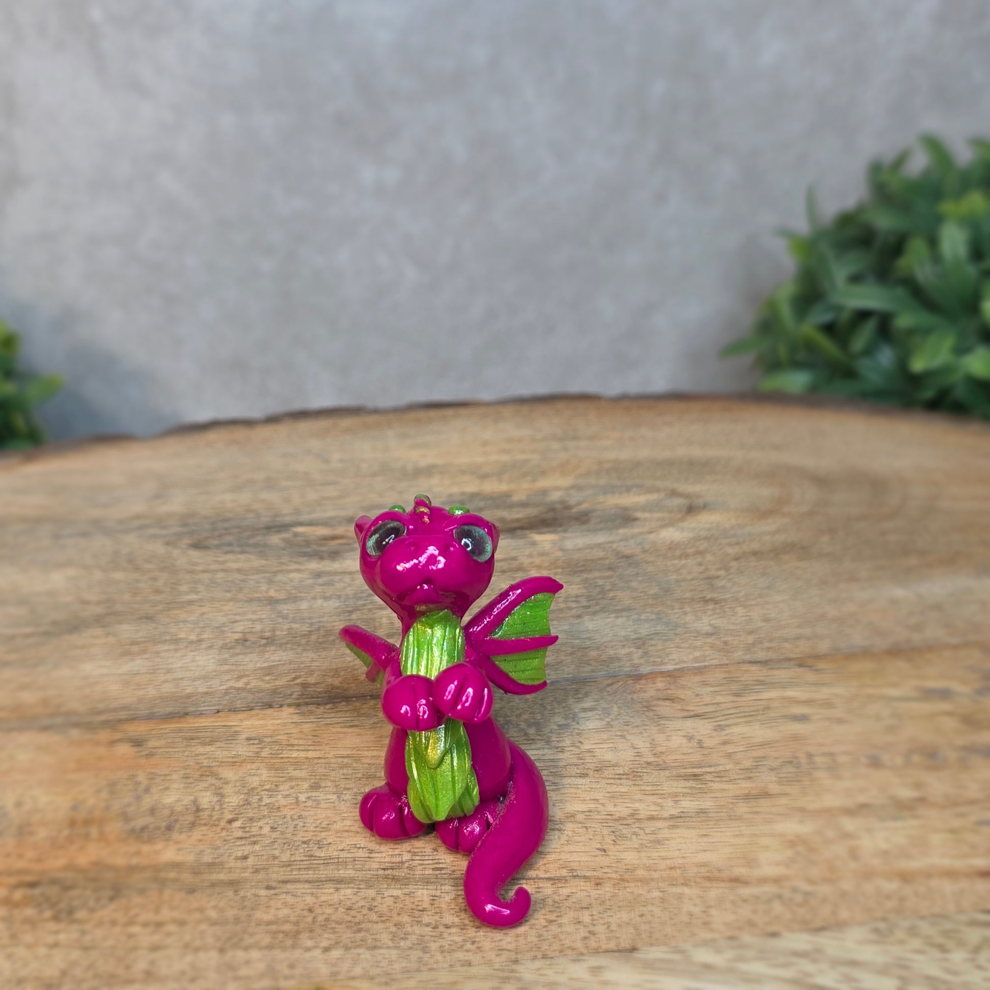 A pink and green clay dragon with a blurred background