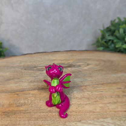 A pink and green clay dragon with a blurred background