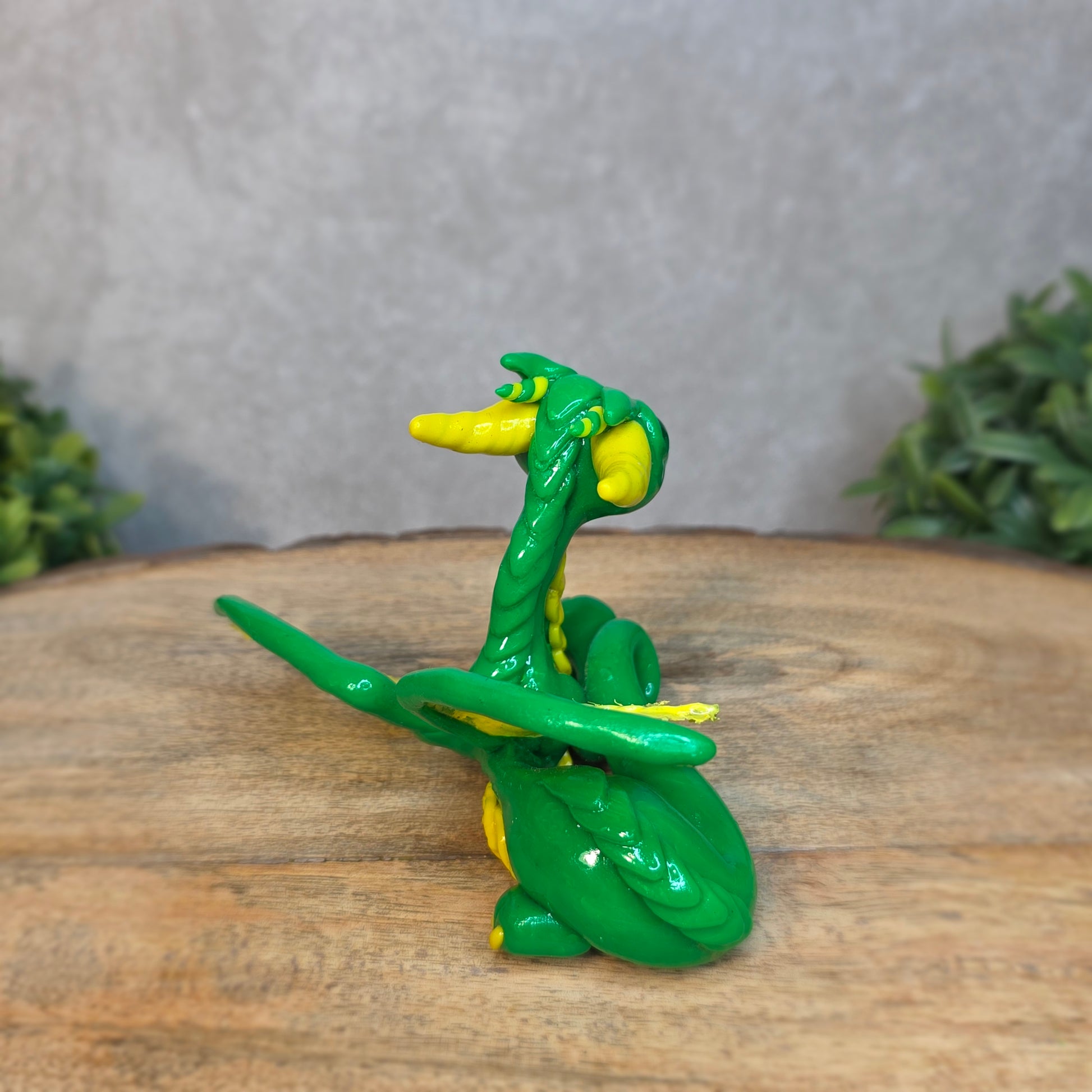 A green and yellow dragon against a blurred wood surface