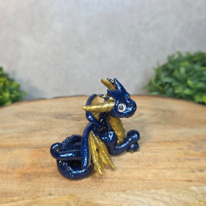 A blue and gold clay dragon against a blurred wood surface